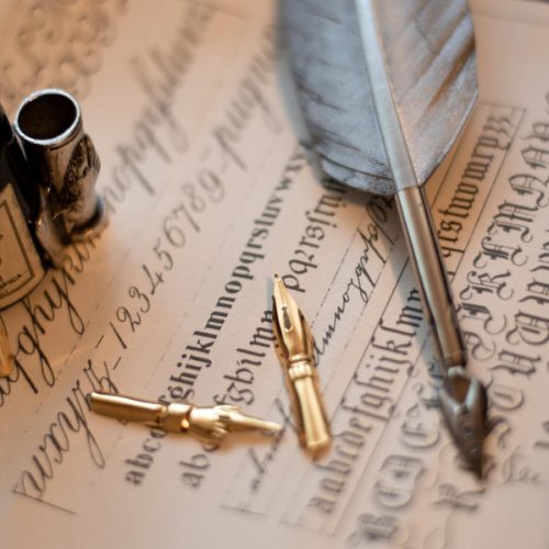 macro-shot-quill-set-ink-bottle-piece-paper-with-calligraphy-it (1)